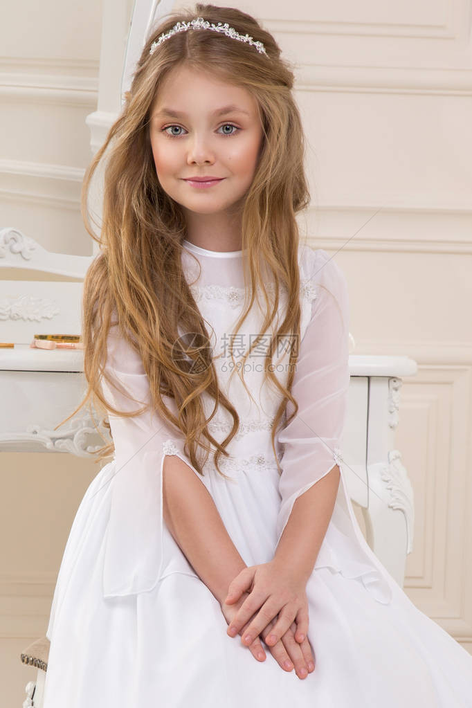 穿着白圣餐礼服的美丽年轻女子模特站在一个图片