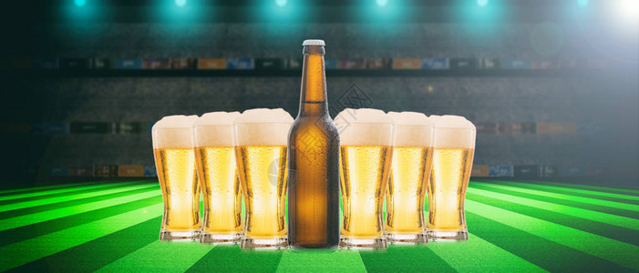 啤酒杯和足球的瓶子足球场背景图片