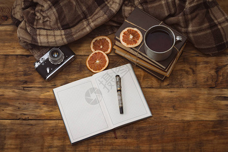 日记用笔书本铝杯用热茶古董照相机和木制背景图片