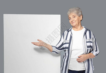 有灰色背景空白广告板的高级妇女图片