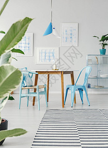 餐厅内部木桌上的蓝色椅子白墙上有条图片