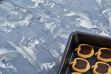 在抽象纹理光背景浅景深选择聚焦的金属饼干片上排列的即食美味苹果形巧克力饼干背景图片