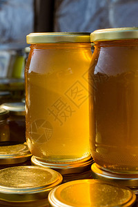 装满新鲜蜂蜜的玻璃罐带盖图片