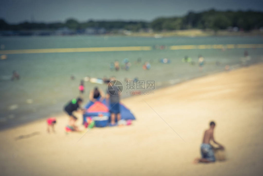 抽象模糊的人在湖边的白沙滩上享受户外活动美国德克萨斯州大草原城滨水林恩溪公园家人搭帐篷图片