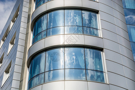 云和天空反映在现代办公楼的窗户上金属灰色和蓝色现代门面抽象背图片