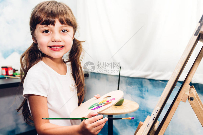 小女孩艺术家在中用彩色调盘和图片