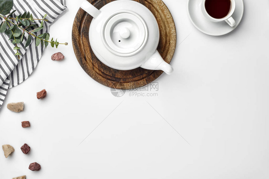 木板上的白瓷茶壶和桌上的白茶杯顶视图复制空间图片