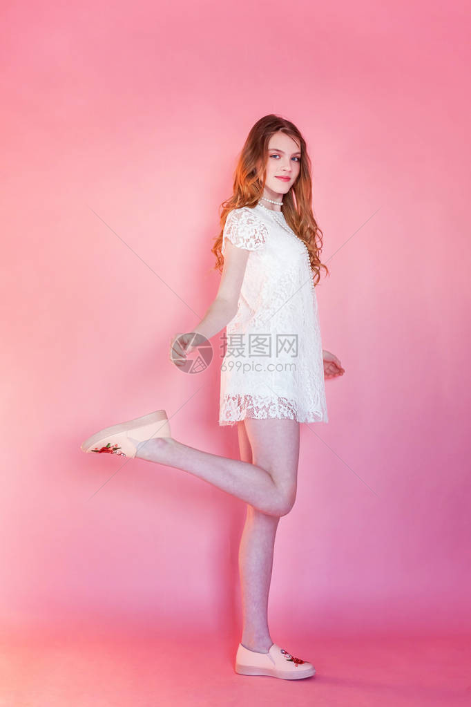 快乐的少女微笑着特写肖像年轻快乐积极的女人穿着白色连衣裙站在粉红色的彩色柔和时尚现代时尚海报背景上欧洲女人积极的人类情感面部图片