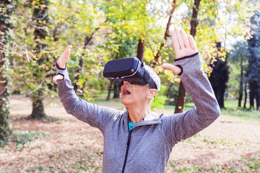 在森林里用虚拟现实耳机和老人用的VR装置给高龄女人带图片