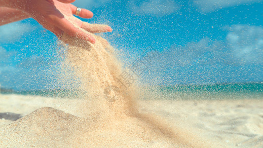 夏天的风将沙子从女孩的手中吹散背景图片