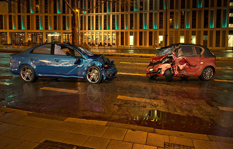 两场车祸夜间在城市位置的道路上撞毁的汽车一辆蓝色轿车对着一辆的城市汽车正面碰撞设计图片