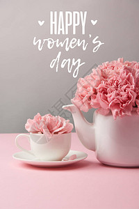 灰色背景的杯子和茶壶中的粉红色康乃馨花图片