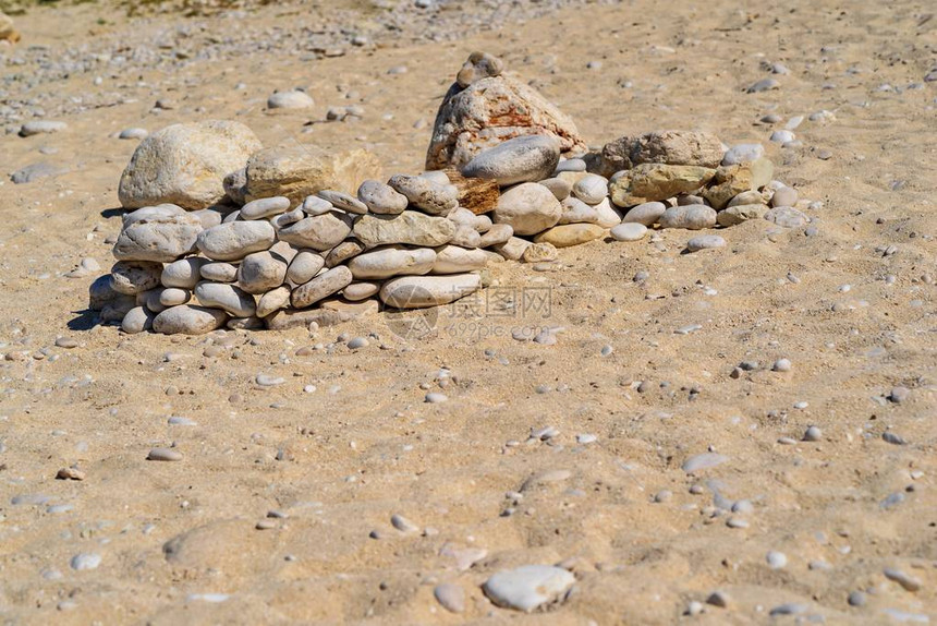 沙滩上铺着抽象的小石头小组或金字塔图片