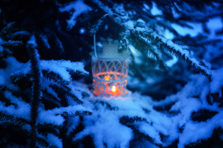 与燃烧的蜡烛的装饰圣诞挂在冬季公园的白雪覆盖的枞树枝上新年节日贺卡图片