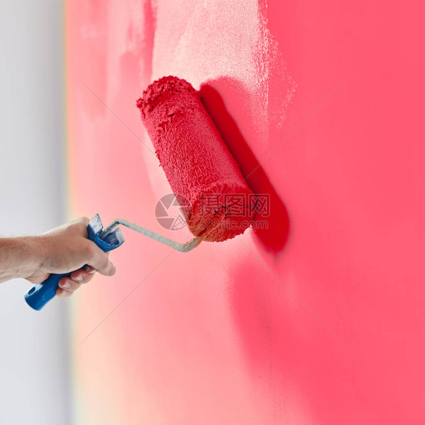 带油漆滚筒的男手绘墙粉刷公寓用粉图片