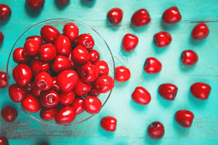 碗里新鲜的红樱桃在旧漆木制桌子上作为季节卡片海报博客网络设计的明亮多图片