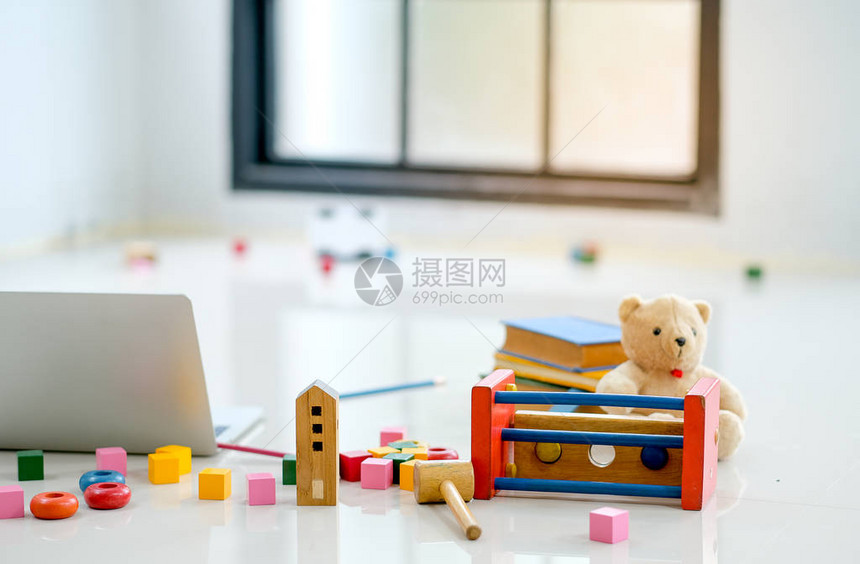 各种玩具和娃被放在玻璃窗前笔记本电脑旁边的地板上图片