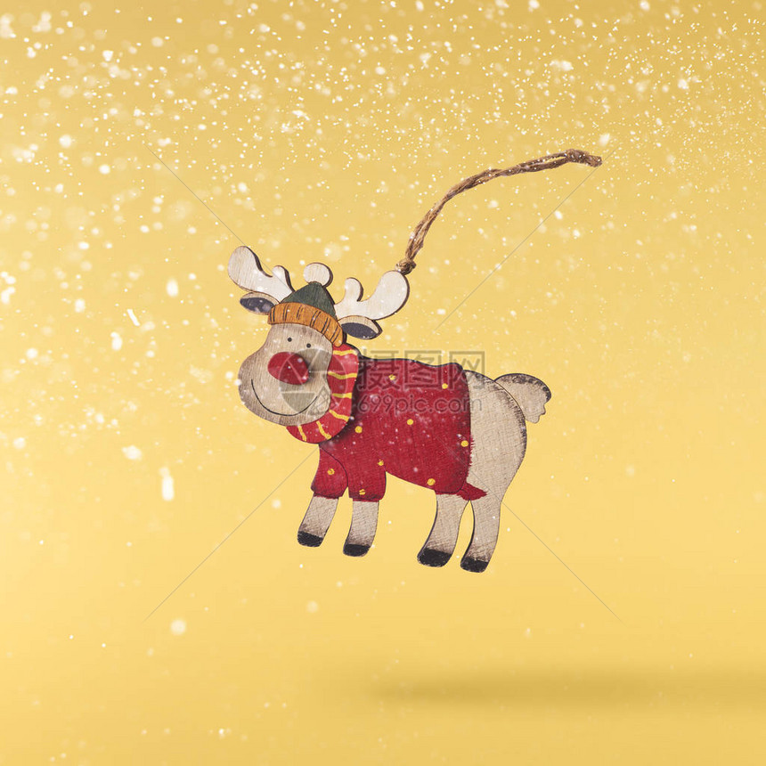 圣诞贺卡概念圣诞玩具鹿装饰在黄色背景上飘落在空中悬浮概念图片