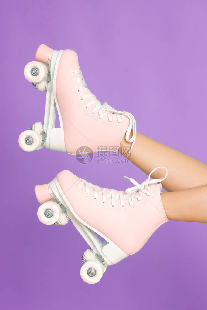 长腿穿着古老的粉红色滚冰滑板在紫罗兰图片