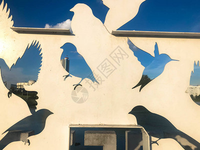 在蓝天前用金属雕刻的鸟鸽的抽象剪影图片