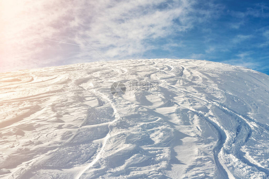 白雪皑的抽象越野滑雪背景与滑雪和滑雪板小径和新的处女粉雪和蓝天背景上的轨道高山丘的早晨日出或图片