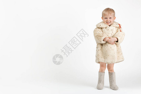 一个穿着苏联羊皮大衣或羊皮大衣和白色背景上的灰色毡靴的蹒跚学步的孩子图片