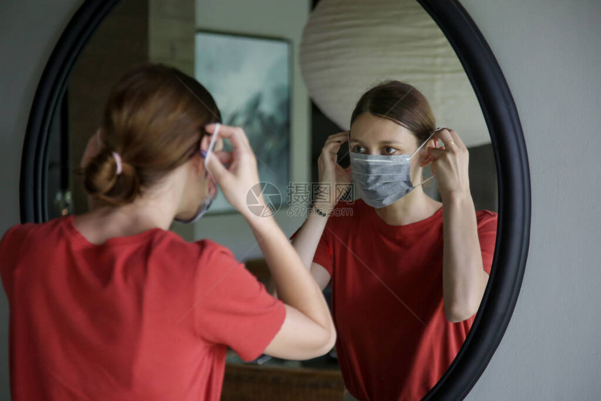 年轻女在走出家门前戴上一次外科手术口罩图片