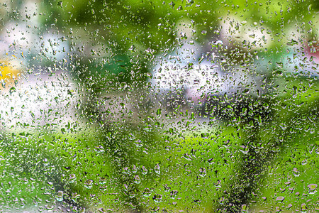 装有雨滴的玻璃窗口形成一个抽象模糊的背景图片