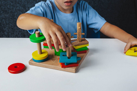 孩子玩蒙台梭利玩具白色背景上的多彩姿的逻辑分拣机婴儿手特写木制几何形状圆形正方形三角形矩图片
