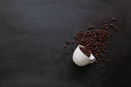 黑木地板背景的白色杯子中的咖啡豆顶部视图背景图片