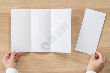 三折小册子模拟传单小册子设计A4大小的纸在商人的手中图片