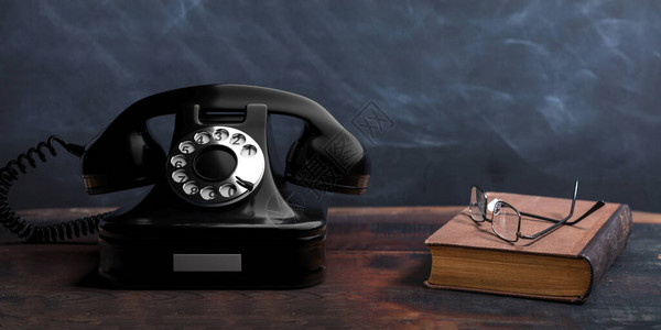 古老的旋转电话旧书和木制桌子上的眼镜图片