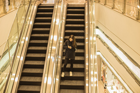 商场电梯女人手机放松背景图片