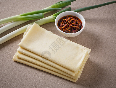 沂蒙山特产一包煎饼和一碗辣椒酱放在桌布上背景