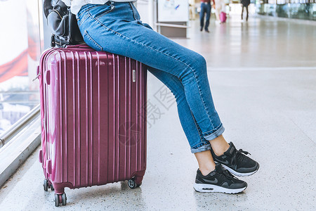 女生牛仔裤坐在行李箱上的女生背景