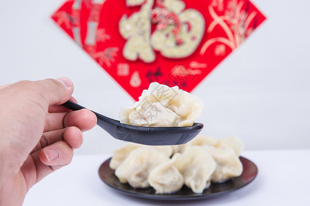 福字为背景的人夹饺子吃的冬至新春节日高清图片