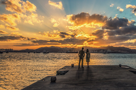 母子海边夕阳下母子牵手漫步于海边背景