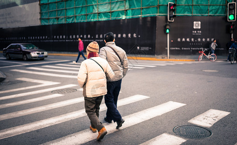 情侣携手互相搀扶过马路的一对老年夫妇背景