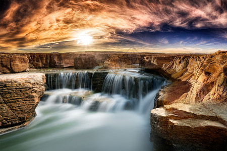 阳光下岩石边的瀑布高清图片