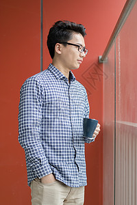 红色卫衣窗前喝咖啡的年轻人背景