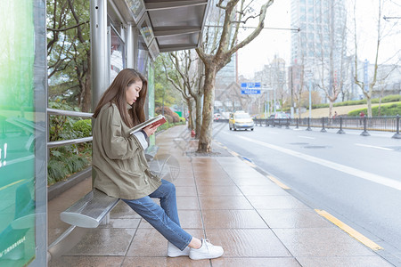 公交亭边等车边看书的女生高清图片