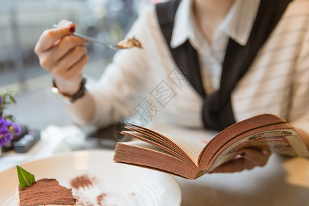 咖啡馆内女孩边吃甜品边看书背景图片