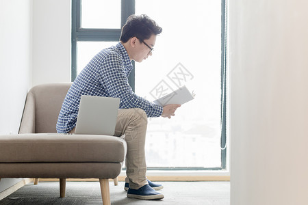 窗边场景坐在沙发上看书的年轻人背景