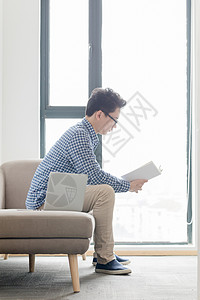 窗边场景坐在沙发上看书的年轻人背景