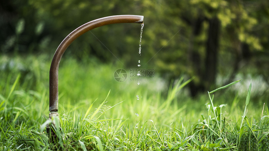 草坪里的水龙头滴水瞬间图片