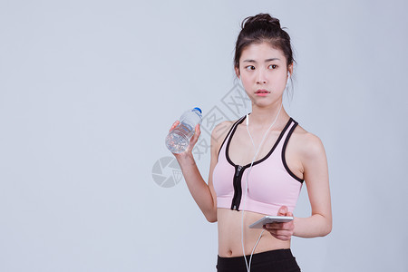 靠着水瓶的女孩青春运动美女休息听音乐背景