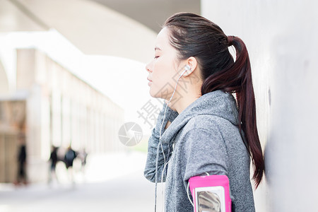 耳机包年轻女子健身后听音乐放松背景