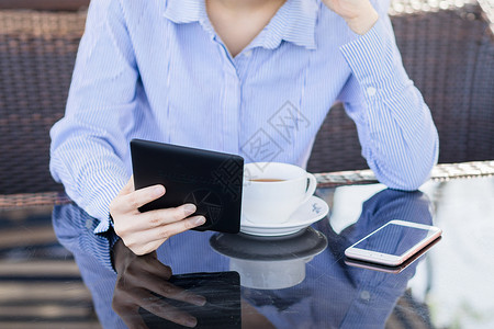 坐着手机年轻女性咖啡店阅读电子书背景