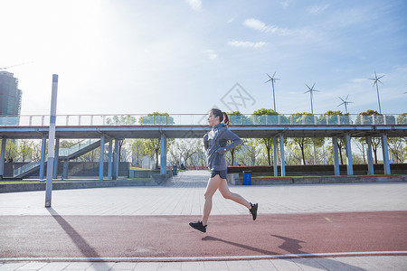 阳光下运动女孩大气在跑道跑步图片