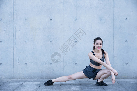 户外运动女孩热身压腿背景图片